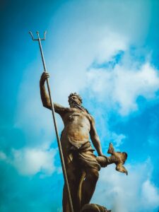 man holding trident statue under white clouds at daytime