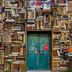 blue wooden door surrounded by book covered wall