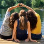 2 women sitting on wooden dock during daytime