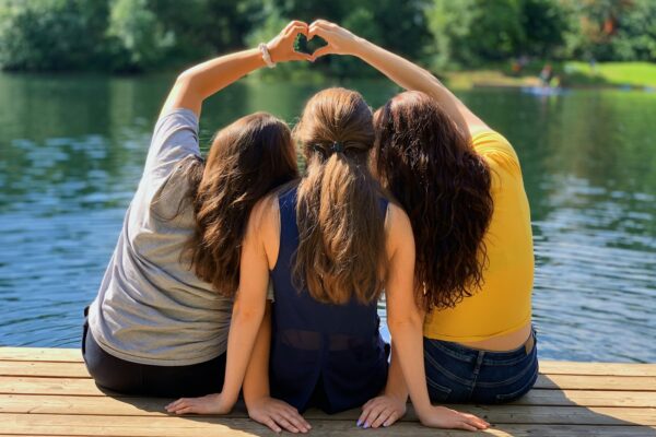 2 women sitting on wooden dock during daytime