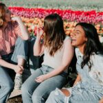 three women sitting wooden bench by the tulip flower field