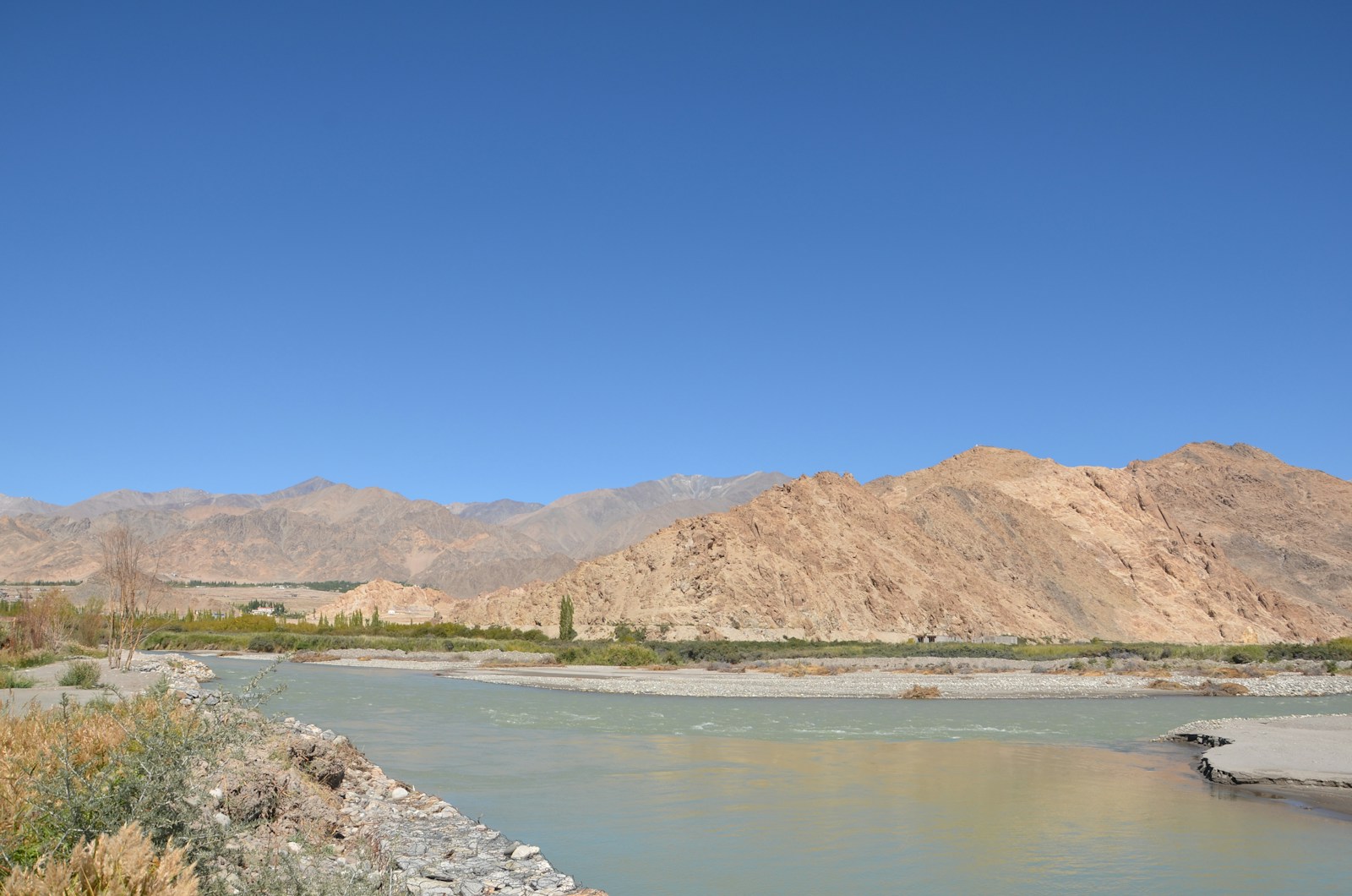 a river running through a desert landscape with mountains in the background