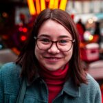 smiling woman wearing eyeglasses and green jacket