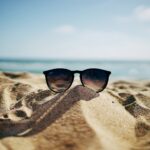 black Ray-Ban Wayfarer sunglasses on beach sand