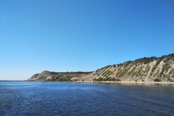 a body of water with a hill in the background