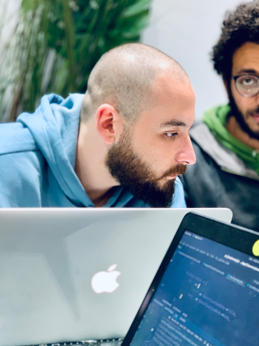 man in blue hoodie looking at macbook