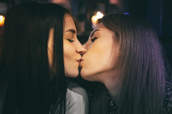 two women kissing each other in a dark room