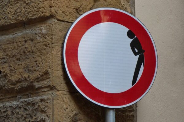 man hiding signage on brick wall