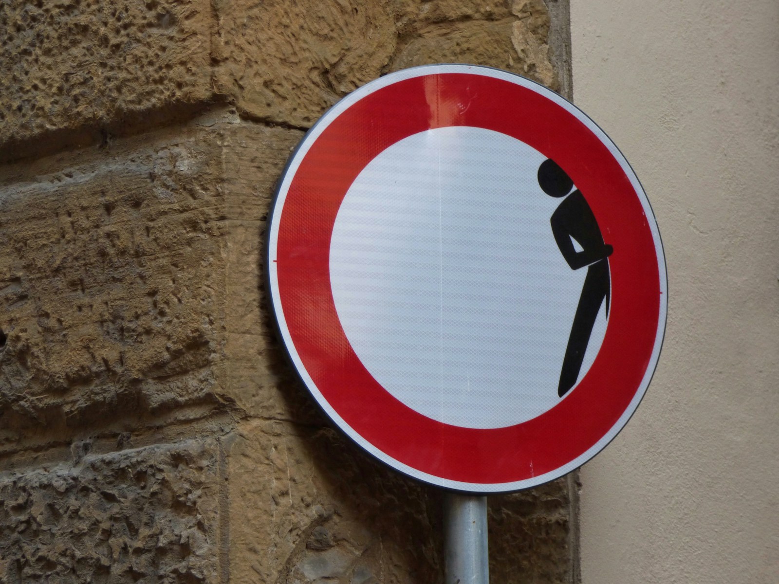 man hiding signage on brick wall