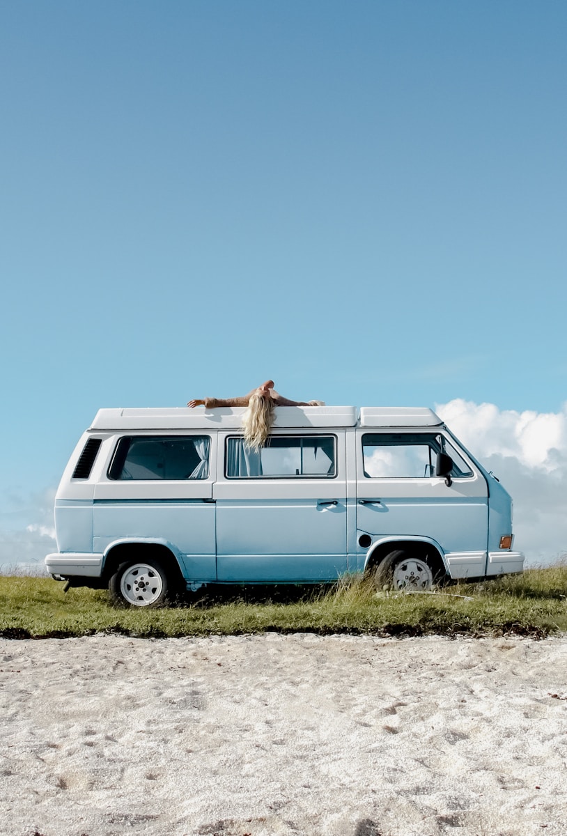 A blue van parked on top of a grass covered field