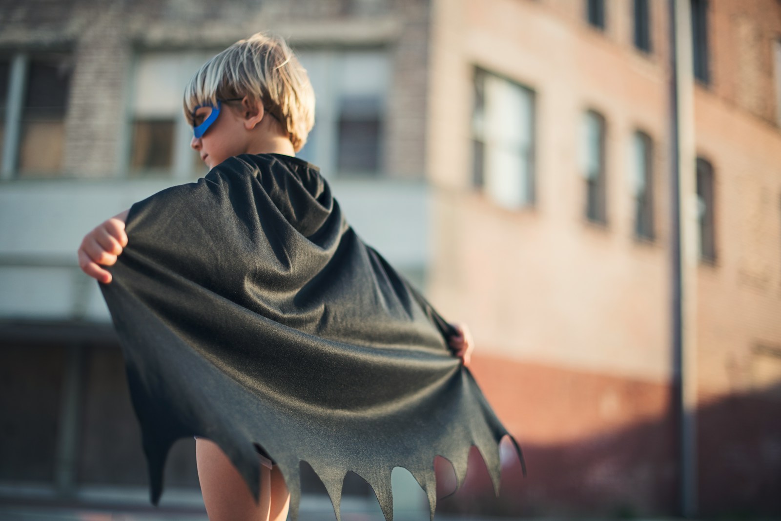 selective focus photography of boy wearing black Batman cape