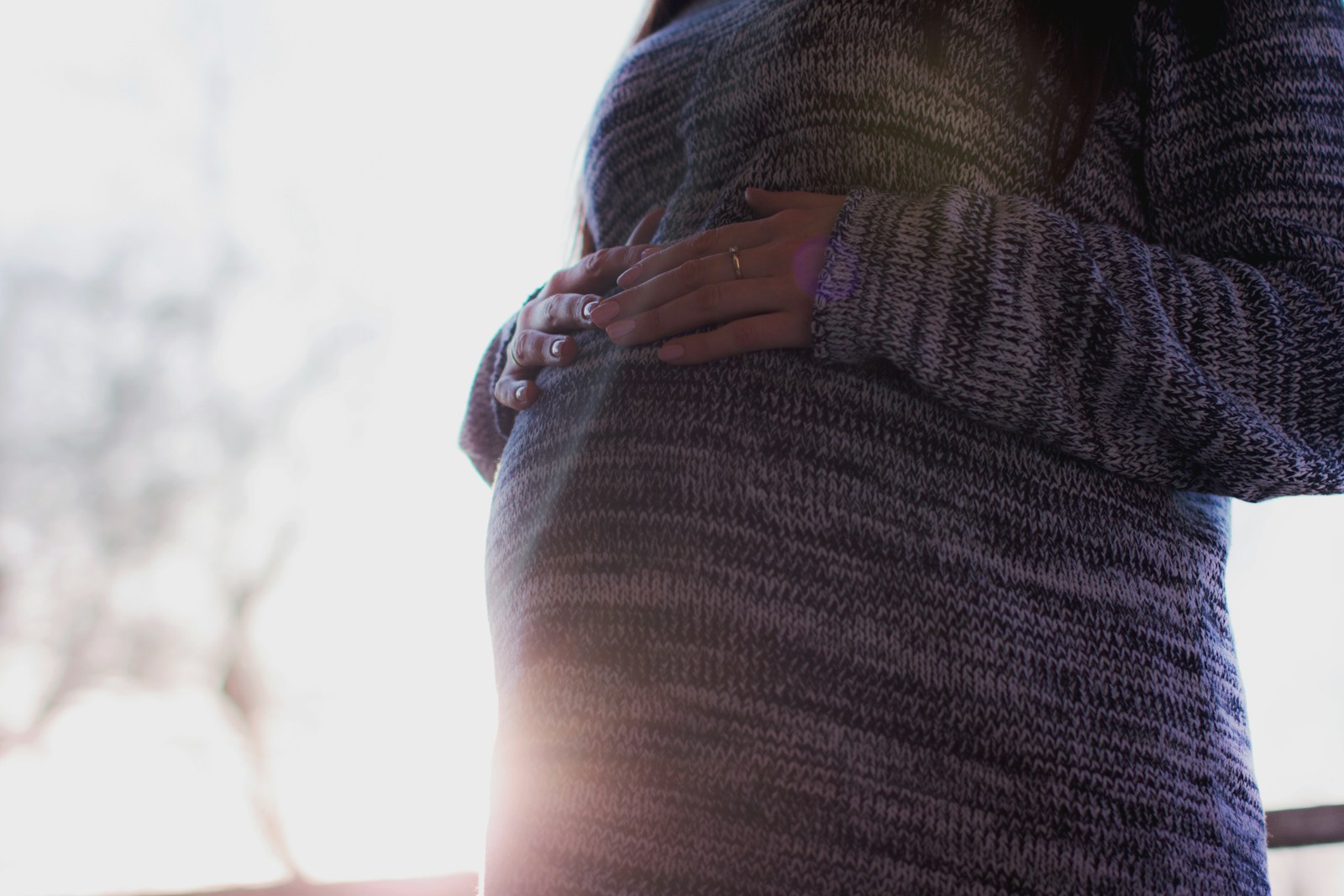 woman holding her prenant tummy during daytime