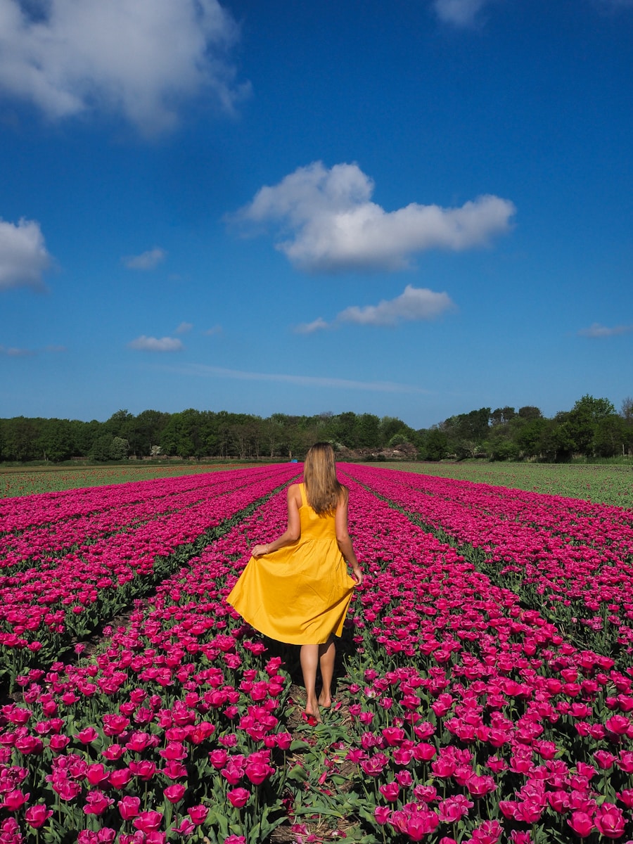 A woman in a yellow dress walking through a field of flowers