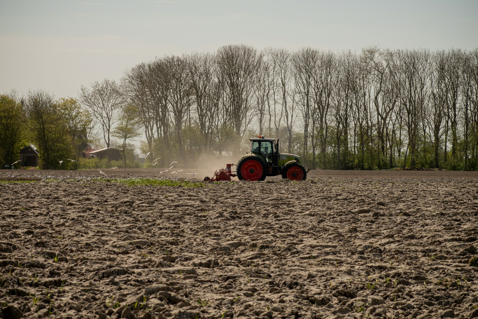 green and orange tractor on brown field during daytime