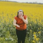 Woman laughs in a field of yellow flowers.