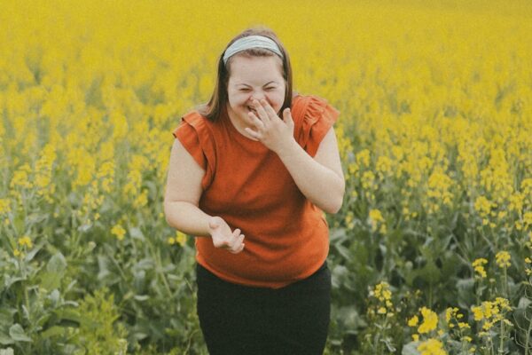 Paul de Leeuw – Nederlandse televisiepersoonlijkheid Woman laughs in a field of yellow flowers.
