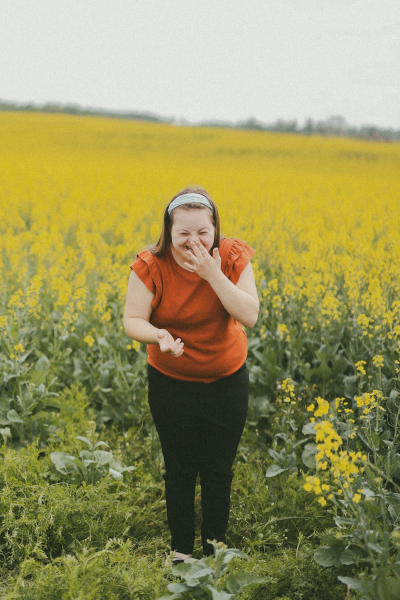 Woman laughs in a field of yellow flowers.
