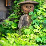 a statue of a bear in a bush with a hat on
