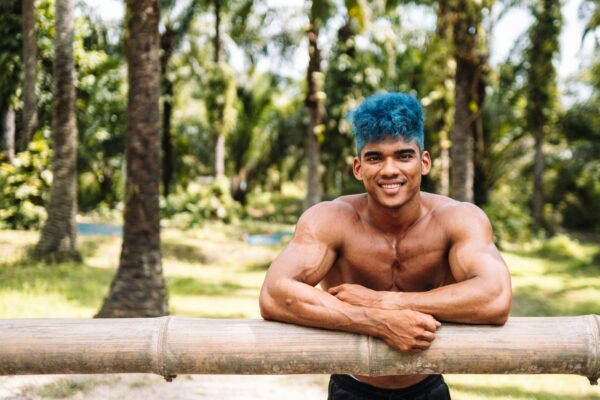 a man with blue hair is leaning on a log